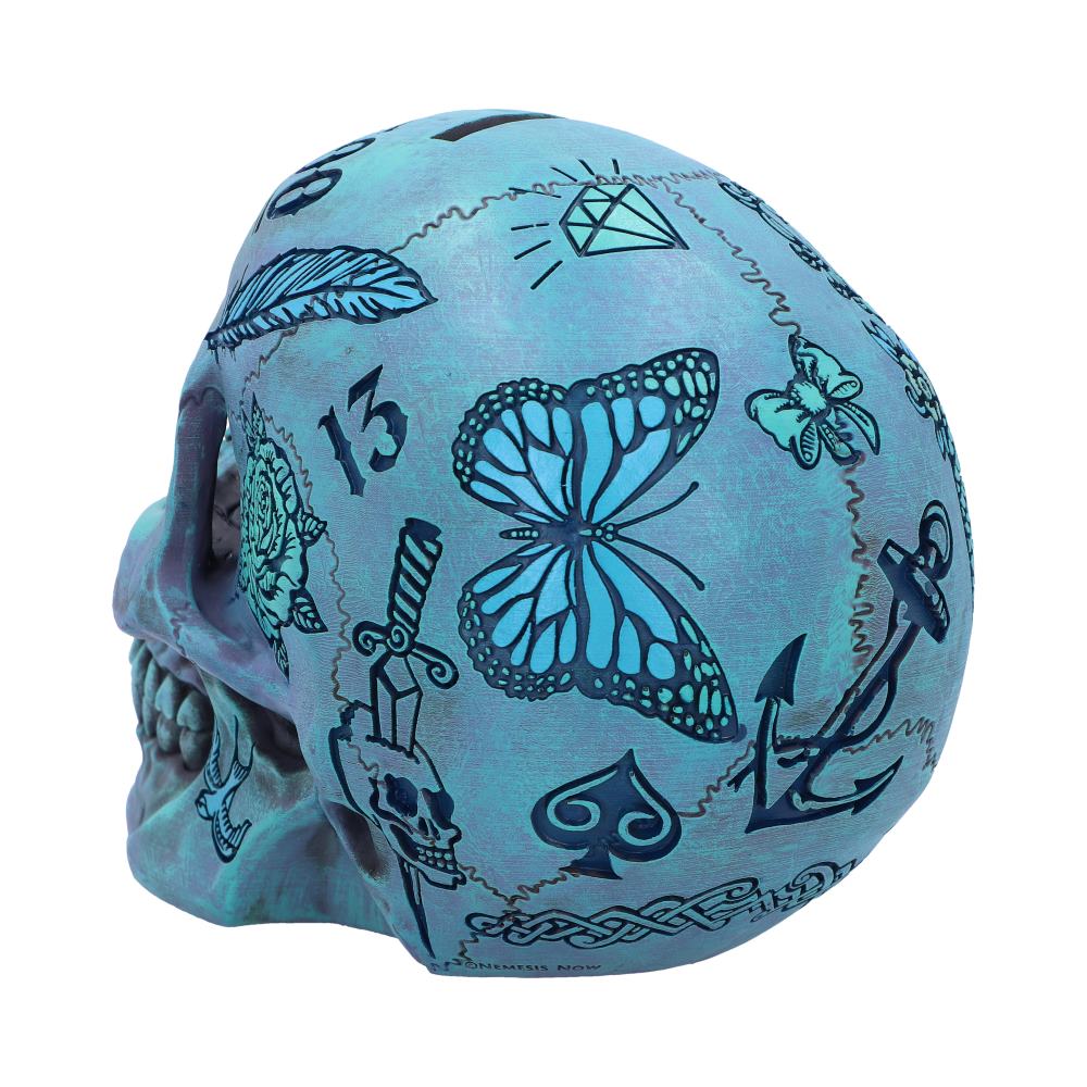 A white background hosts a blue skull, this is a back view which is angled to show the detailed etchings carved onto the left side of it. There is a butterfly, a spade, the number 13 and several more on display.