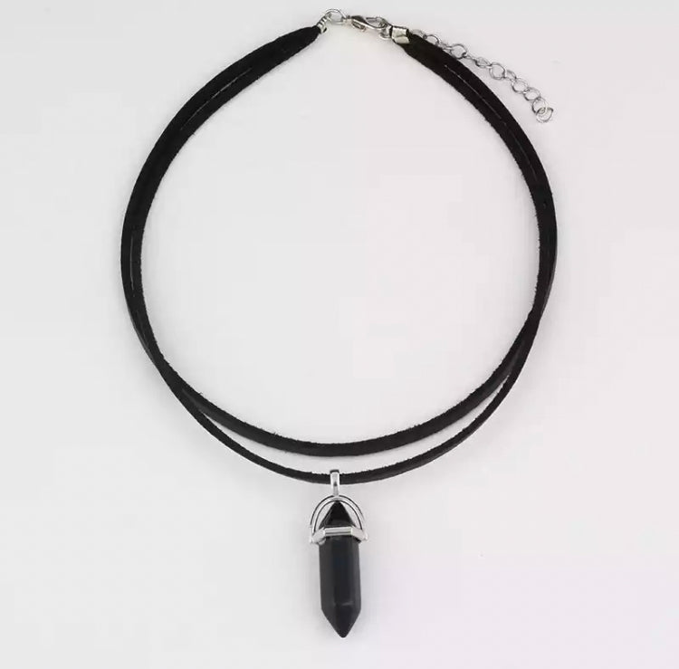 On a white background sits a necklace that has a black stone attached it to. There is a metal clasp for fastening that is attached to a double banded cord chain.