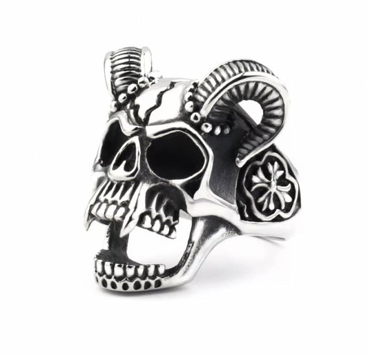 A solid chunky looking ring in the shape of a vampire skull sits on a white background. It is silver in colour and features very detailed engravings including horns and teeth. The ring is weighty to wear and of high quality.