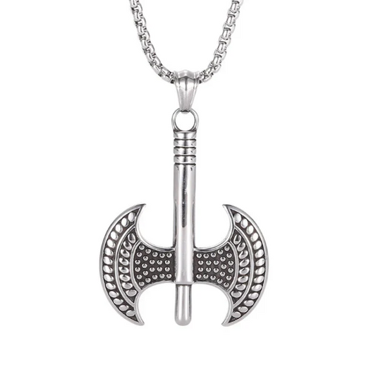 Upon a plain white background is a shiny silver coloured axe necklace which is a two headed axe. The head of the axes have a raised circular pattern engraved onto them and the whole thing is solid and weighty to hold.  