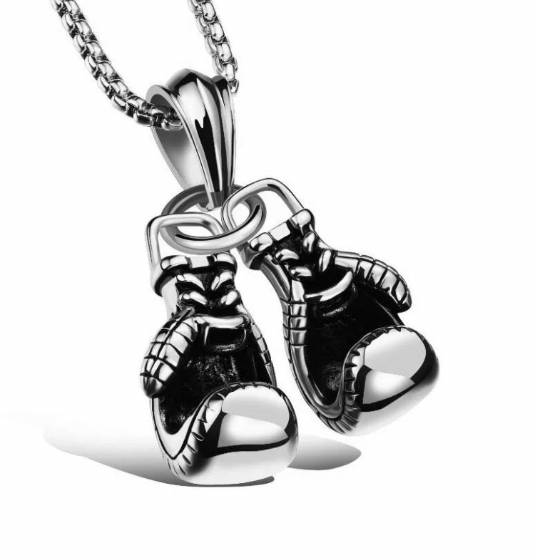 A necklace with a pair of boxing gloves pendant is against a plain white background. These 2 gloves are solid and made of stainless steel with detailed markinga on the gloves themselves. 