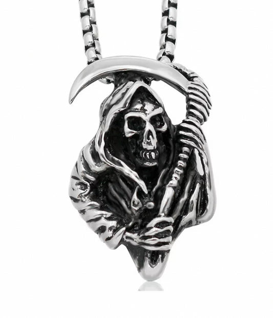 Upon a white background is a pendant in the shape of a grim reaper. This is a solid stainless steel item attached to a chain of the same material. The reaper is holding a scythe and is wearing a hooded cloak and looks menacing.