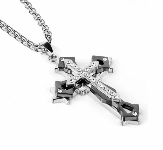 A chunky looking cross pendant sits on a white background. This is three crosses on top of each other with them all being slightly different sizes. The top cross has a design that makes it look as if jewels are embedded onto it.