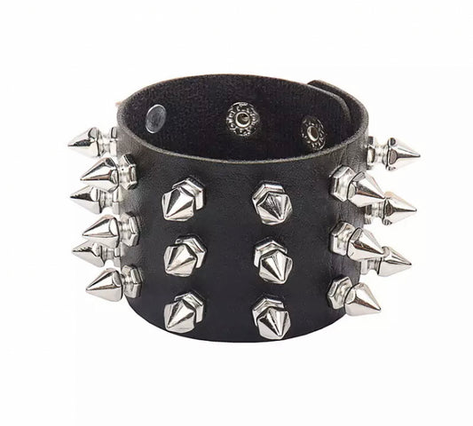 A black leather wide bracelet is on a white background. Attached to the outside circumference are silver coloured spikes. There are 3 per row going around it.