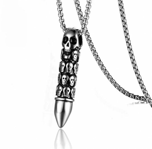 A silver coloured pendant in the shape of a bullet is on a plain white background. Attached to a sturdy looking chain this item also features skull carvings on the bullet with a plain tip. Solid to hold and slightly weighty this item is unique.
