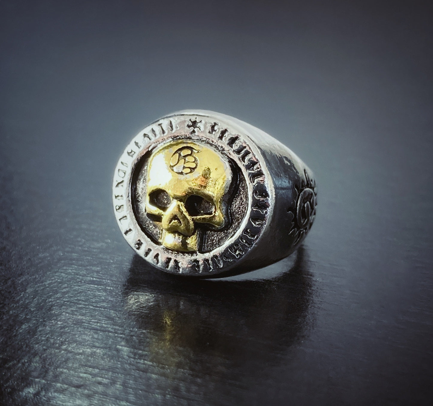 A skull which is gold in colour is featured on the top part of a solid looking ring. The main body of the item is silver in colour and it is fairly chunky to look at. 