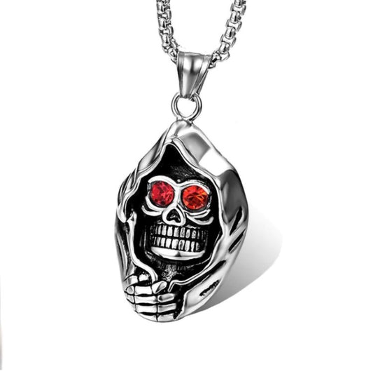 A close up of a cloaked skull pendant necklace. This item is silver in colour and made of solid stainless steel. The eyes are red zircon stones and the markings detailing the face are very detailed. There is a sturdy lloking chain attached to this pendant.