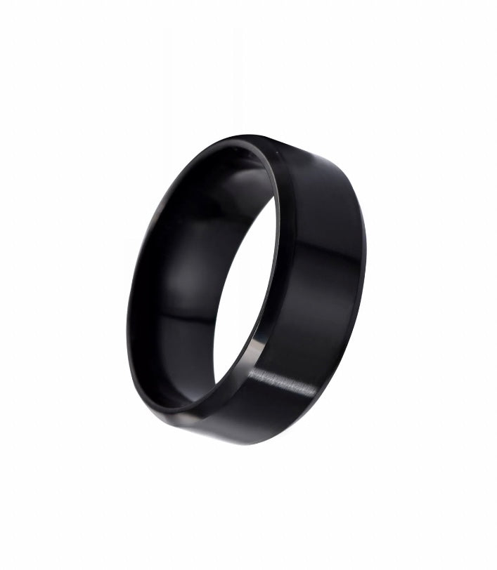 An angled view of a black ring is on show here. It is plain in design and is a band style ring. 