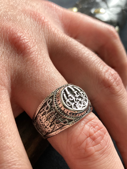 A angled view of a chunky ring on a finger showing the bear claw design that features on both the top and side of the ring. Silver in colour this is a detailed and solid looking item.