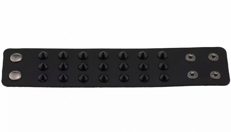 A wide black bracelet is at full stretch on a white surface. You can see the full length and detail of it including the black spikes and the fastening studs.