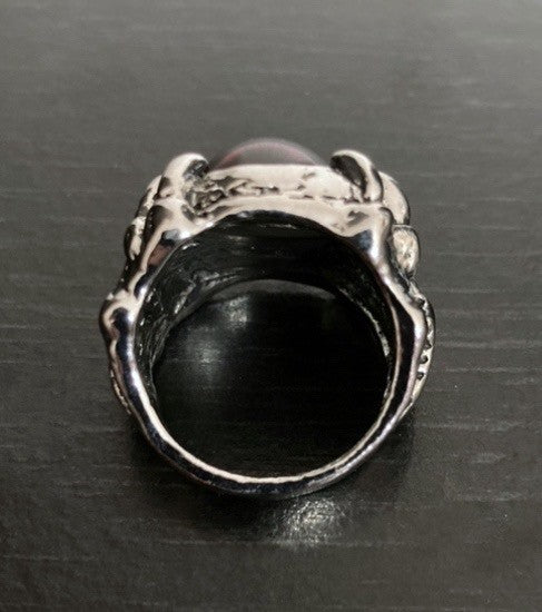 This view is of the back of a silver coloured dragon claw ring. You can see the narrow band that slips onto the finger and that is is plain inside the ring. The ring is chunky, solid and weighty to hold and wear.