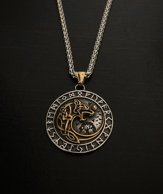 A circular stainless steel pendant which has a gold coloured wolf engraving in the middle and silver coloured runes around the outside. On a black background you can really see the intricate details of the item which feels weighty to hold. 