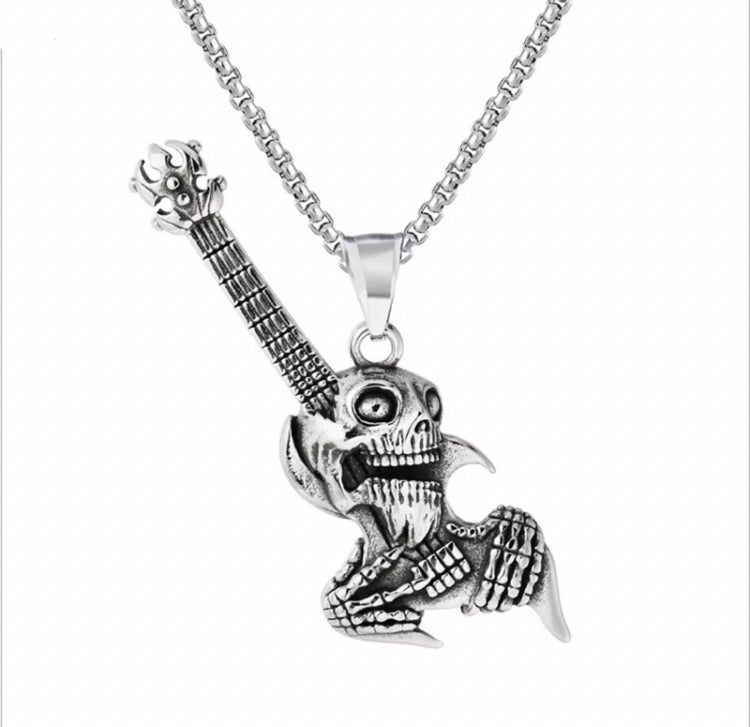 A silver coloured chain is attached to a pendant in the shape of a skulls head and upper body with a guiter embedded into its head.