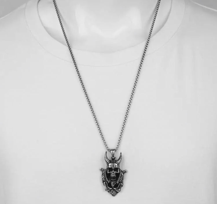 A necklace being worn is on display with a skull hanging from it. The main piece is solid and has hollowed out eyes, a helmet with horns and is carrying 2 axes. If you hold the irem you can feel a weightiness and quality to it. 