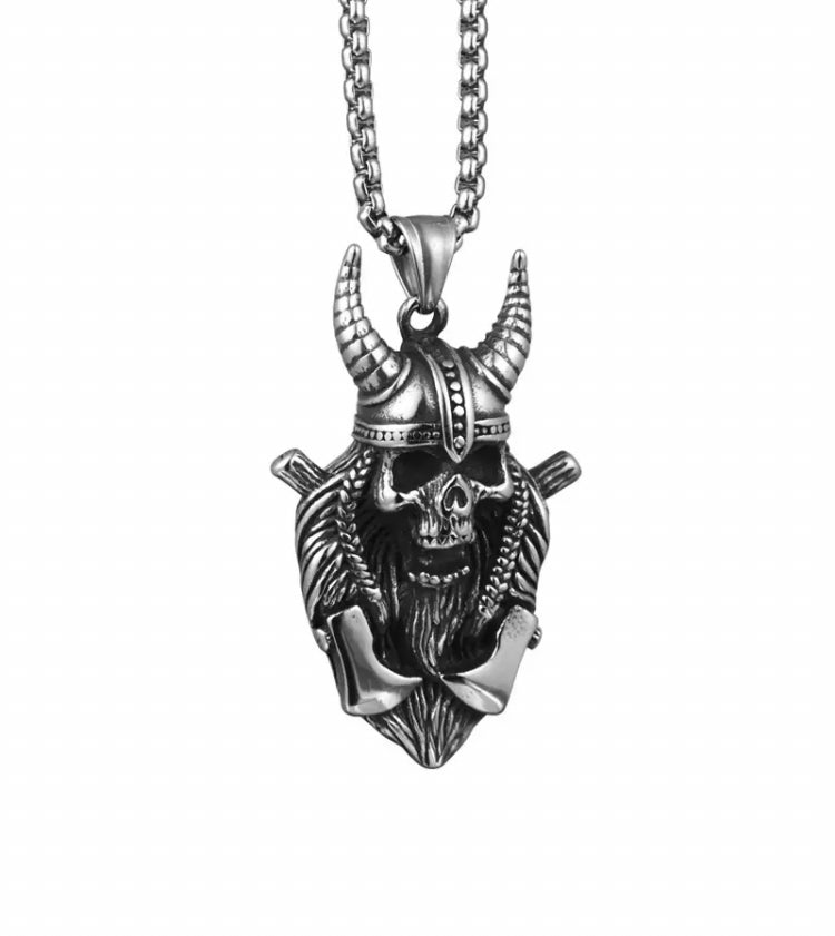 A skull pendant is hanging on a white background attached to a silver colour chain. It looks ferocious with a horned helmet, sunken eye holes and a gaping mouth. 