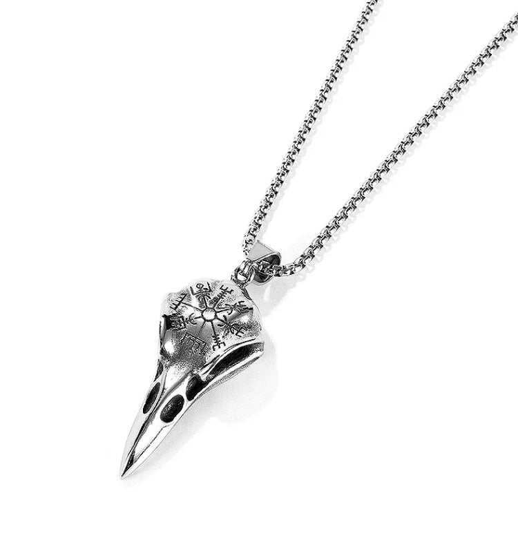 A angled view of a necklace complete with chain and raven skull pendant. All is silver in colour and is light to hold. When touching it you can feel the engraved design that sits on top of the skull.