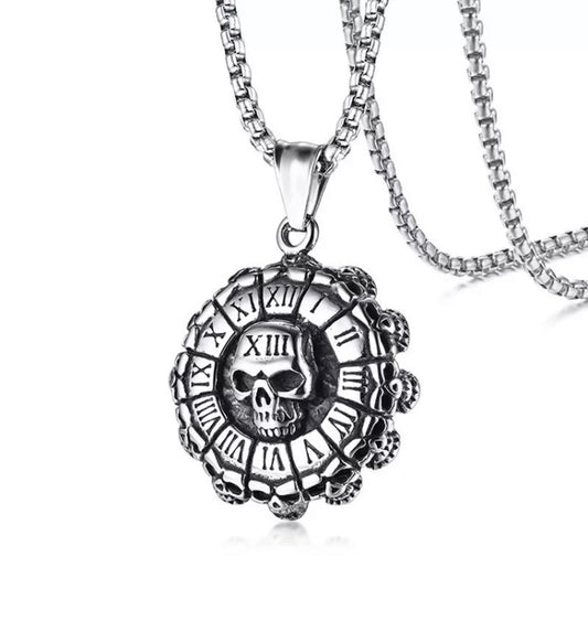 On a white background sits a circular pendant that is shaped like a beer bottle cap. There is a skull featured in the middle and Roman numerals going around the outside like a clock face. Number thirteen in the numerals is imprinted on the skull