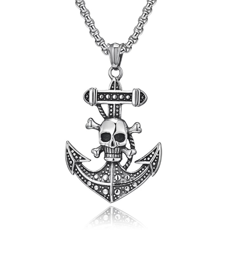 A anchor pendant with a skull and crossbones on the shaft of it sits on a white background. There is a chain attached to it and both are a shiny silver colour. This is a Chunky solid piece and is weighty in the hand to hold.