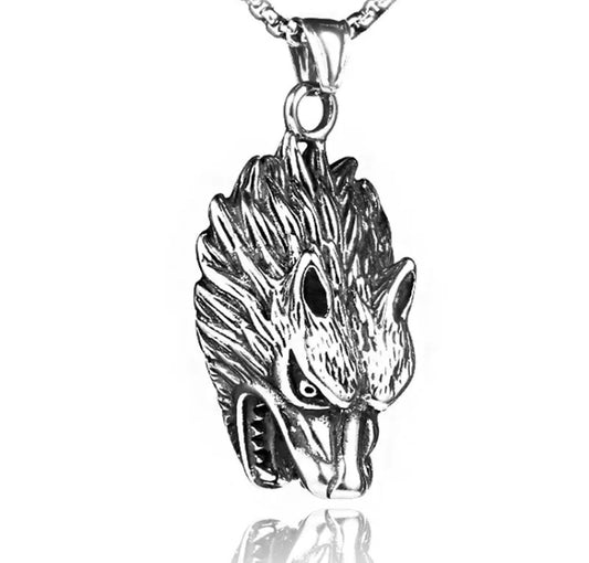 A wolfs head pendant is hanging on a white background. The head hangs downwards so the mouth which is open and snarling faces down the body when worn. It is silver in colour and chunky looking.