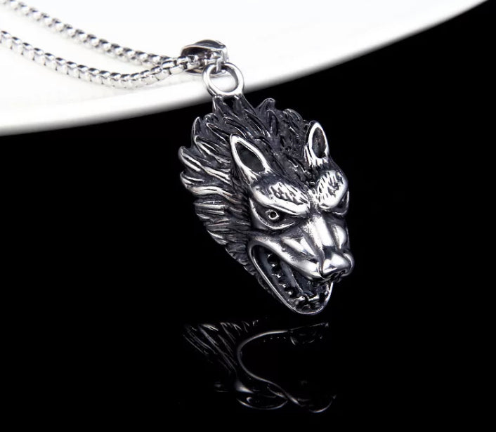 A close up of a wolfs head pendant. With very detailed features on the face this wolf looks to be snarling. You can see the chain which is attached to it and when worn the wolfs head would dangle downwards.