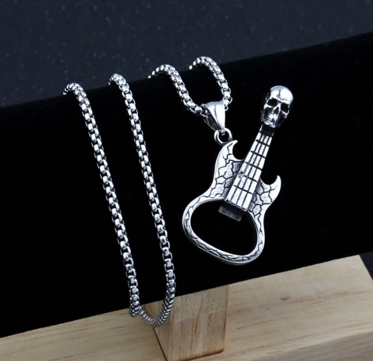 A black surface has a chain wrapped around it with a bottle opener in the shape of a guitar attached to it. This is silver in colour and is lighweight to hold.