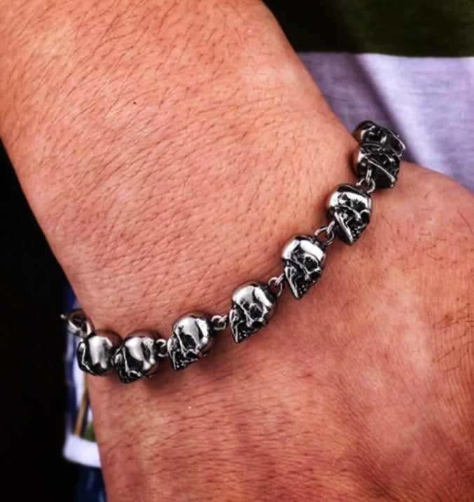 On a wrist sits a skull head bracelet. Solid looking and silver in colour the skulls go all the way around with a link between each one. it is a shiny silver colour and although chunky isnt too heavy to wear.