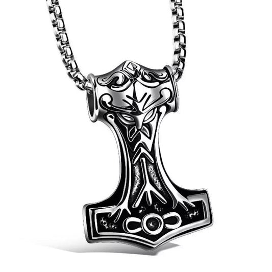 On a white background sits a pendant in the shape of Thors hammer which is silver in colour. There is an inscription of the Algiz rune as well as patterning engraved onto it. It is stainless steel and lightweight to hold and wear with a sturdy looking chain.