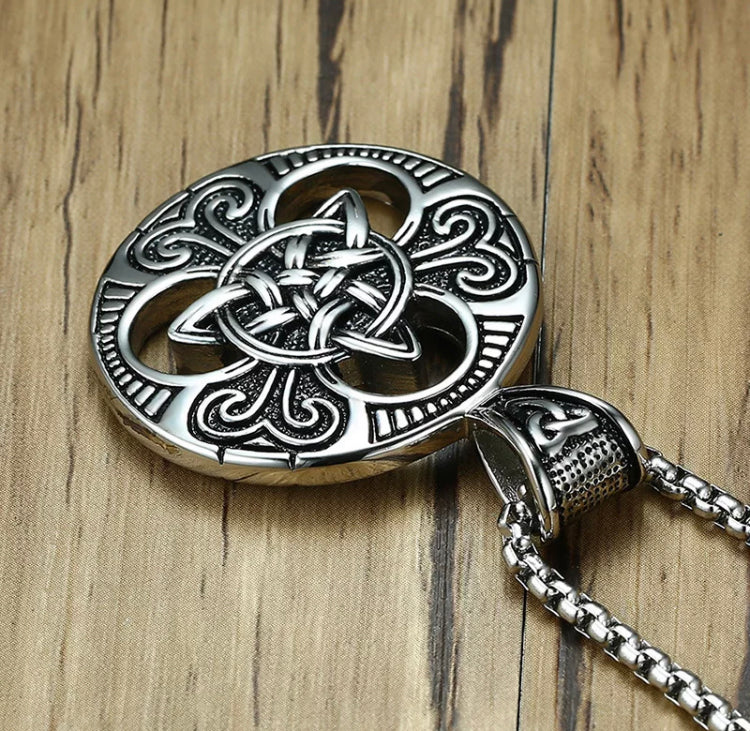 A view of the top of a circular pendant with a triqueta design in the middle of it. This is attached to a sturdy looking chain and the whole thing is silver in colour. 