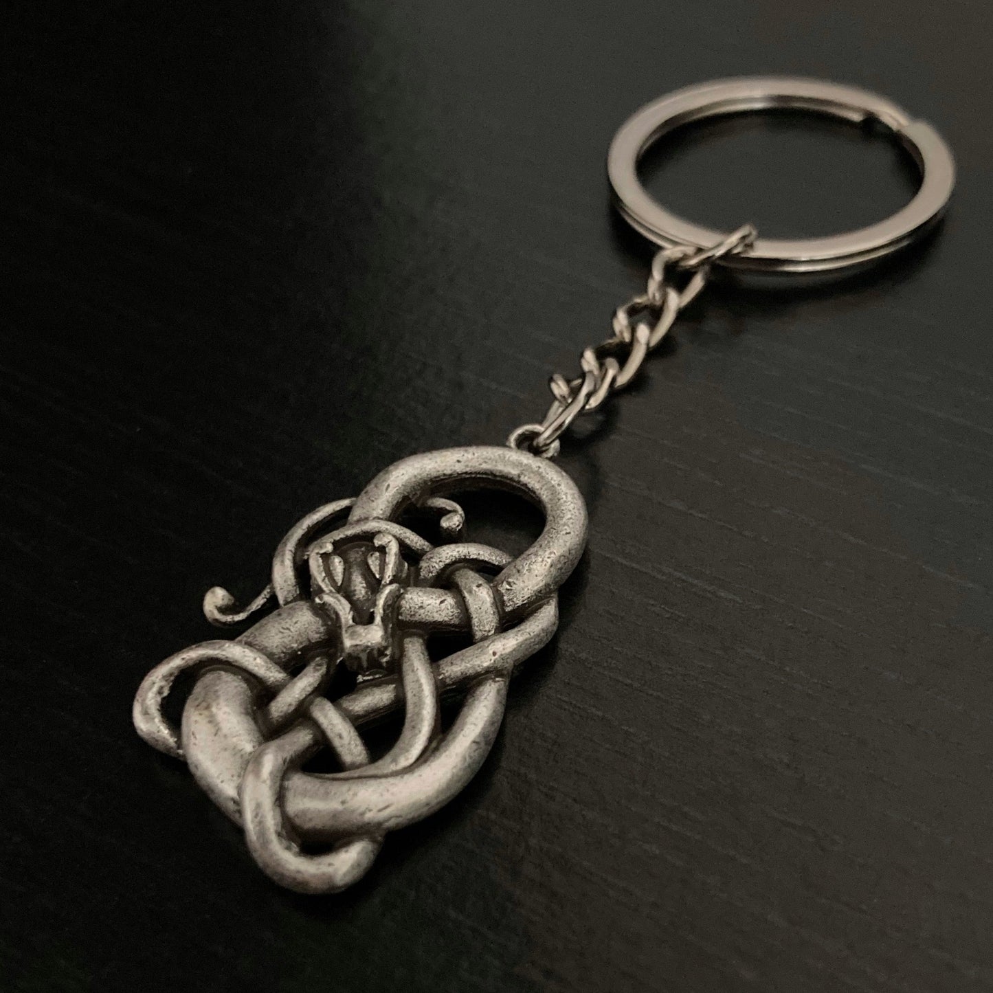 A solid looking keyring which features a snake wrapped around a infinity symbol with its head in the centre of the design. 